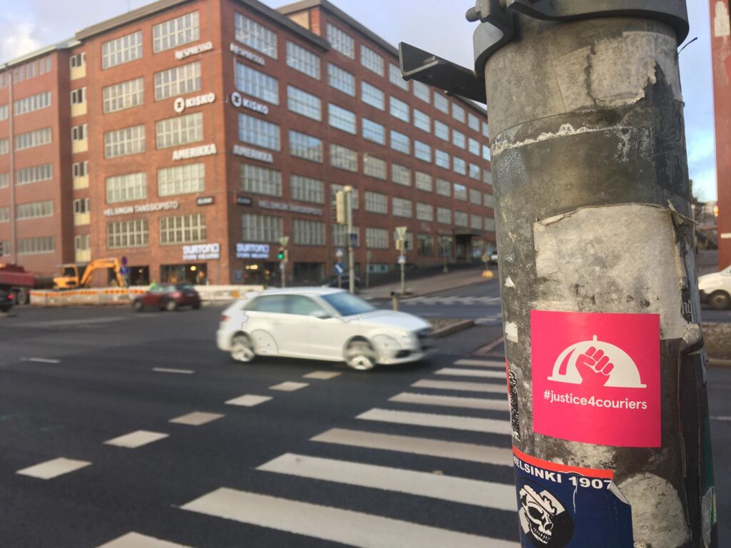 #justice4couriers-tarroja näkyy monissa liikennevalotolpissa ainakin Helsingissä. Useimmiten tarrat esiintyvät juurikin paikoissa, joissa polkupyöräilijät ylittävät autoteitä – ja odottavat vuoroaan valoissa.