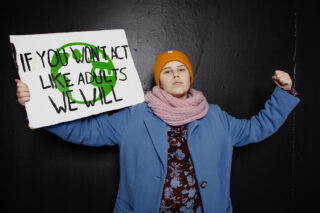 Falenius pitelee käsissään "If you won't act like adults we will" -kylttiä.