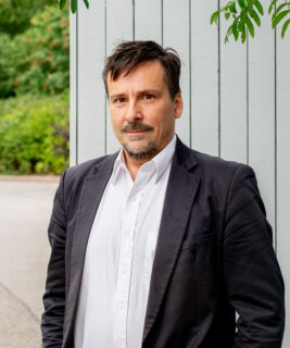 Matinpuro katsoo kameraan, taustalla seinä ja kaupunkiluontoa.