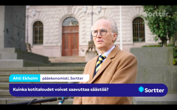 Ruskeaan villakangastakkiin pukeutunutta vanhempaa miestä haastatellaan Suomen pankin edessä