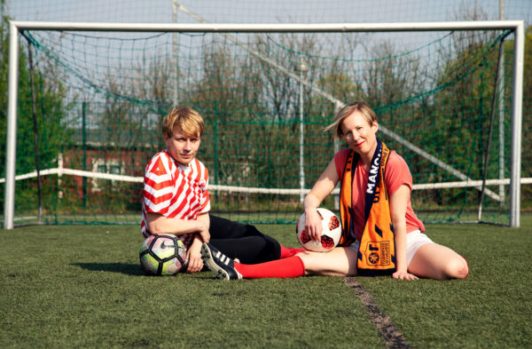 Ruohonen ja Tervonen istuvat maassa jalkapallokentällä maalin edessä.