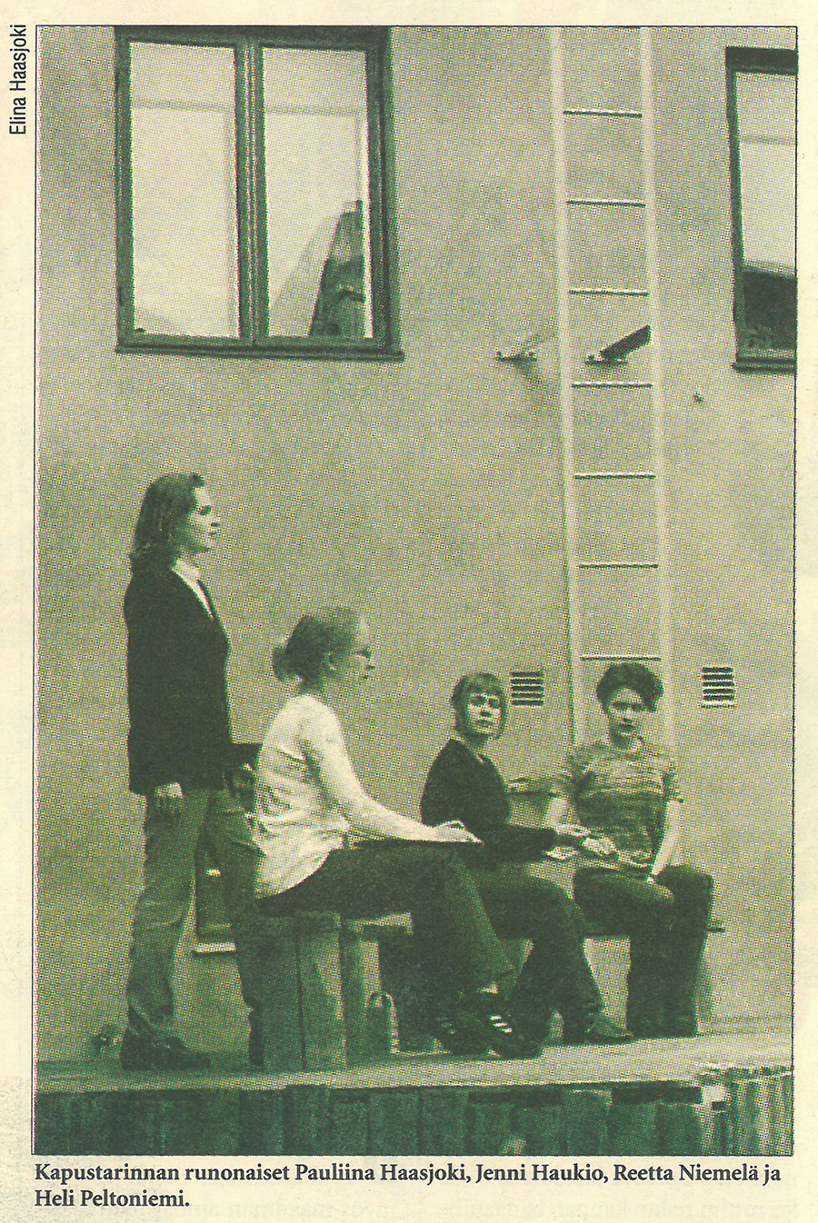 Neljä henkilöä istuu talon edustalla.