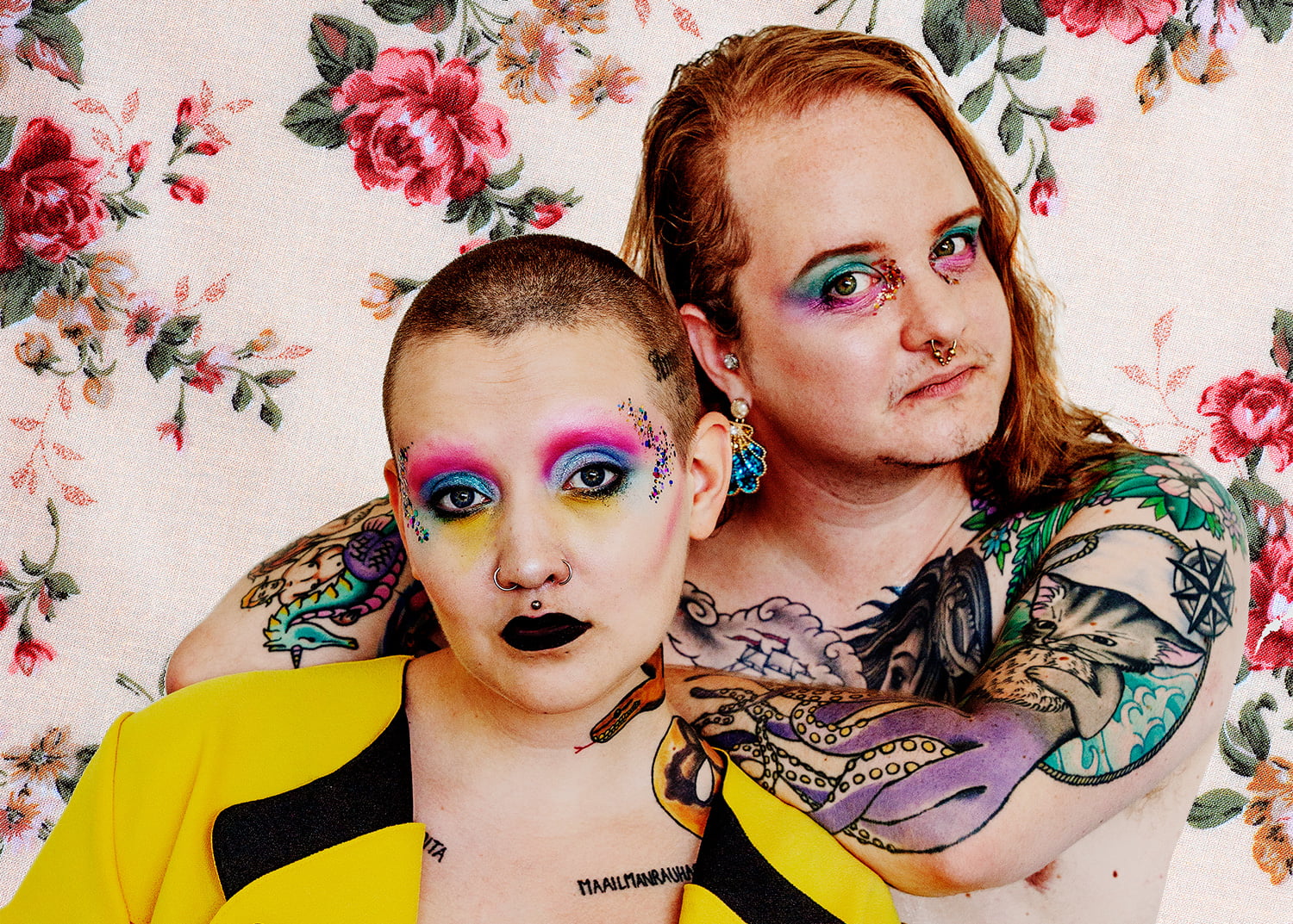 Rantanen ja Eriksson katsovat kameraan, Eriksson nojaa Rantasen olkapäähän. Taustalla kukkakuvioinen tausta.