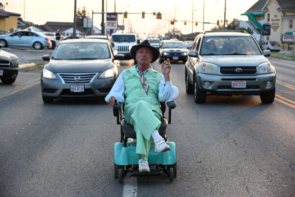 Mies ajaa autojen edessä sähköpyörätuoliila