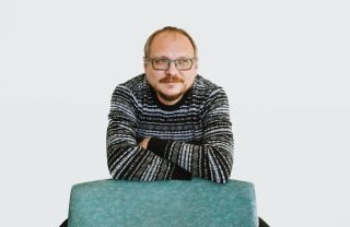 Andrei Kureichik katsoo pois kamerasta, nojaa tuolin selkämykseen.