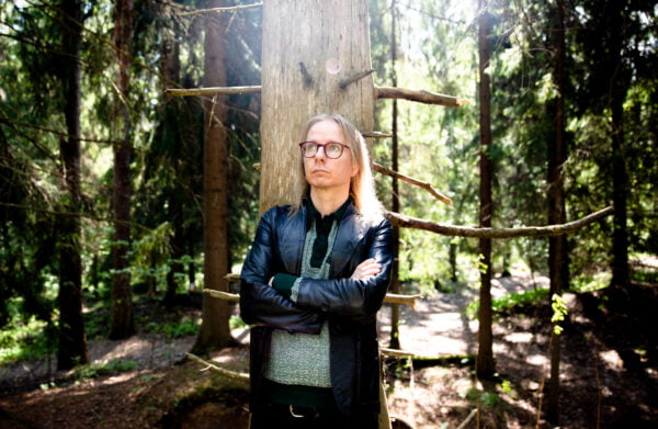Mikko Nenonen seisoo metsässä, aurinko paistaa.