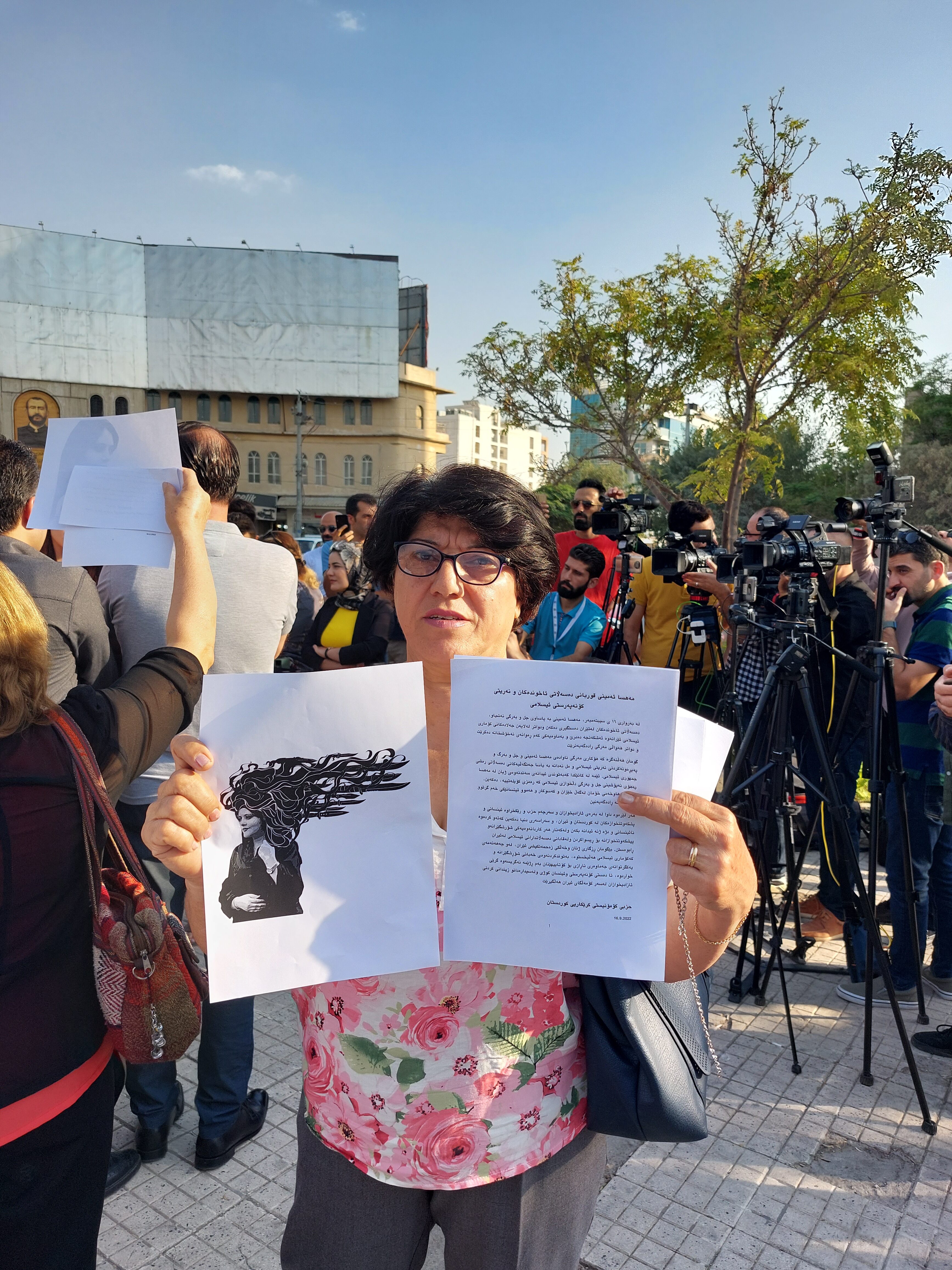 Nagada Osman pitelee kahta Jinan kuvaa ja tekstilappua käsissään mielenosoituksessa.