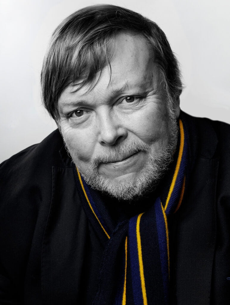 Mustavalkoinen valokuva Markus Leikolasta, kaulahuivi sini-keltainen.