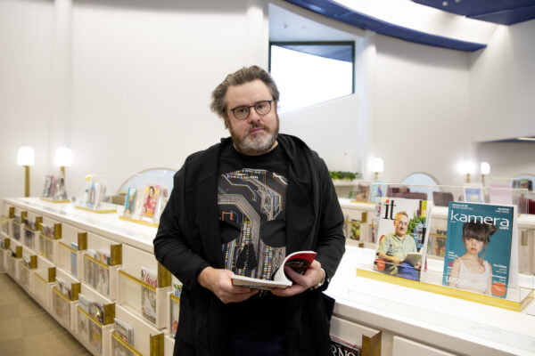 Kimmo Jylhämö pitelee lehteä kädessään, seisoo kirjaston lehtisalissa.