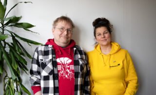 Tuomas Rantanen ja Satu Silvo katsovat kameraan hymyillen, taustalla valkoinen seinä.