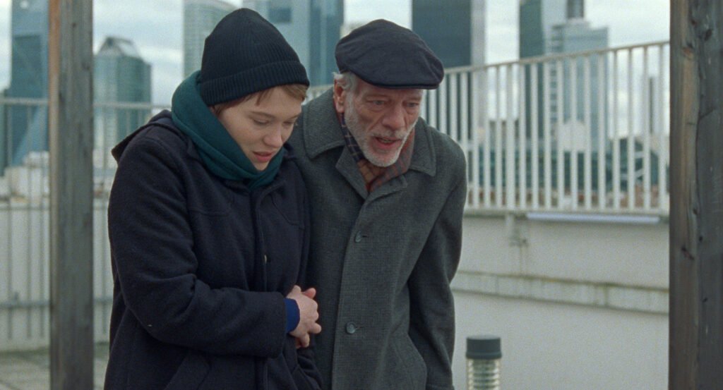 Léa Seydoux ja Pascal Greggory kävelevät rinnakkain harmaassa säässä ulkona.