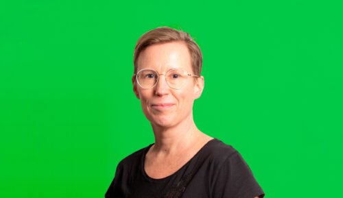 Johanna Ruohonen katsoo kameraan hymyillen, vihreä tausta.