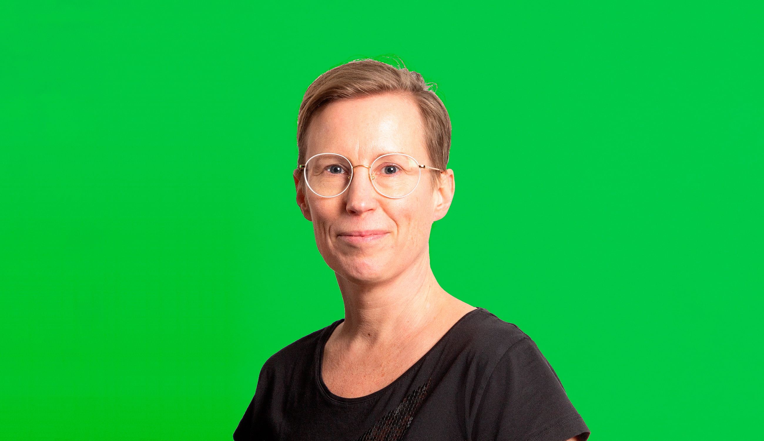 Johanna Ruohonen katsoo kameraan hymyillen, vihreä tausta.