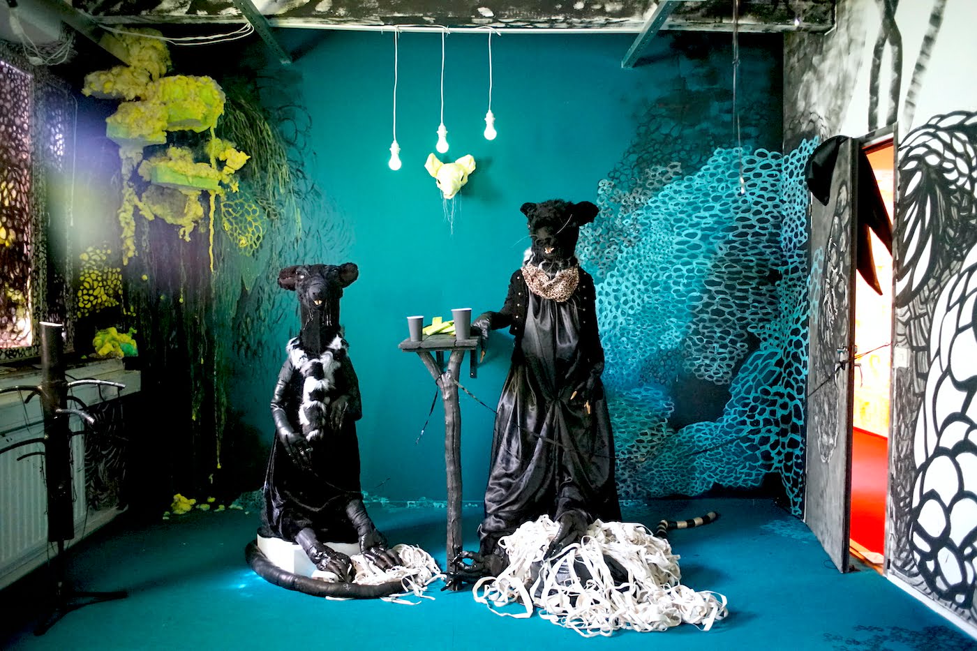 Installaatio. Kaksi rottahahmoa seisoo keskellä turkoosia huonetta.