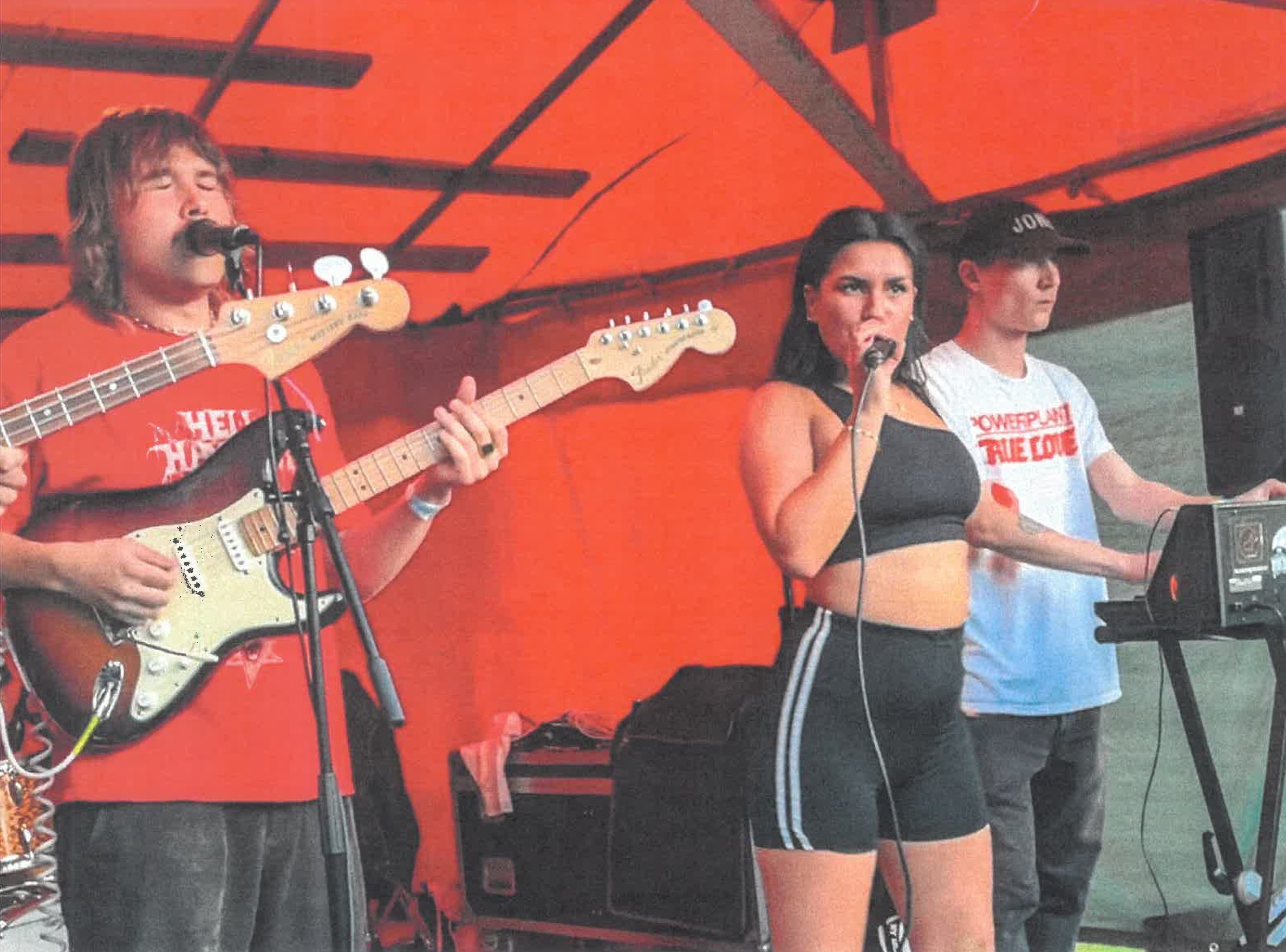 Bändi esiintyy punaisessa teltassa auringonpaisteessa.