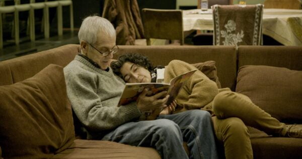 Nainen ja mies lukevat kirjaa sohvalla. 