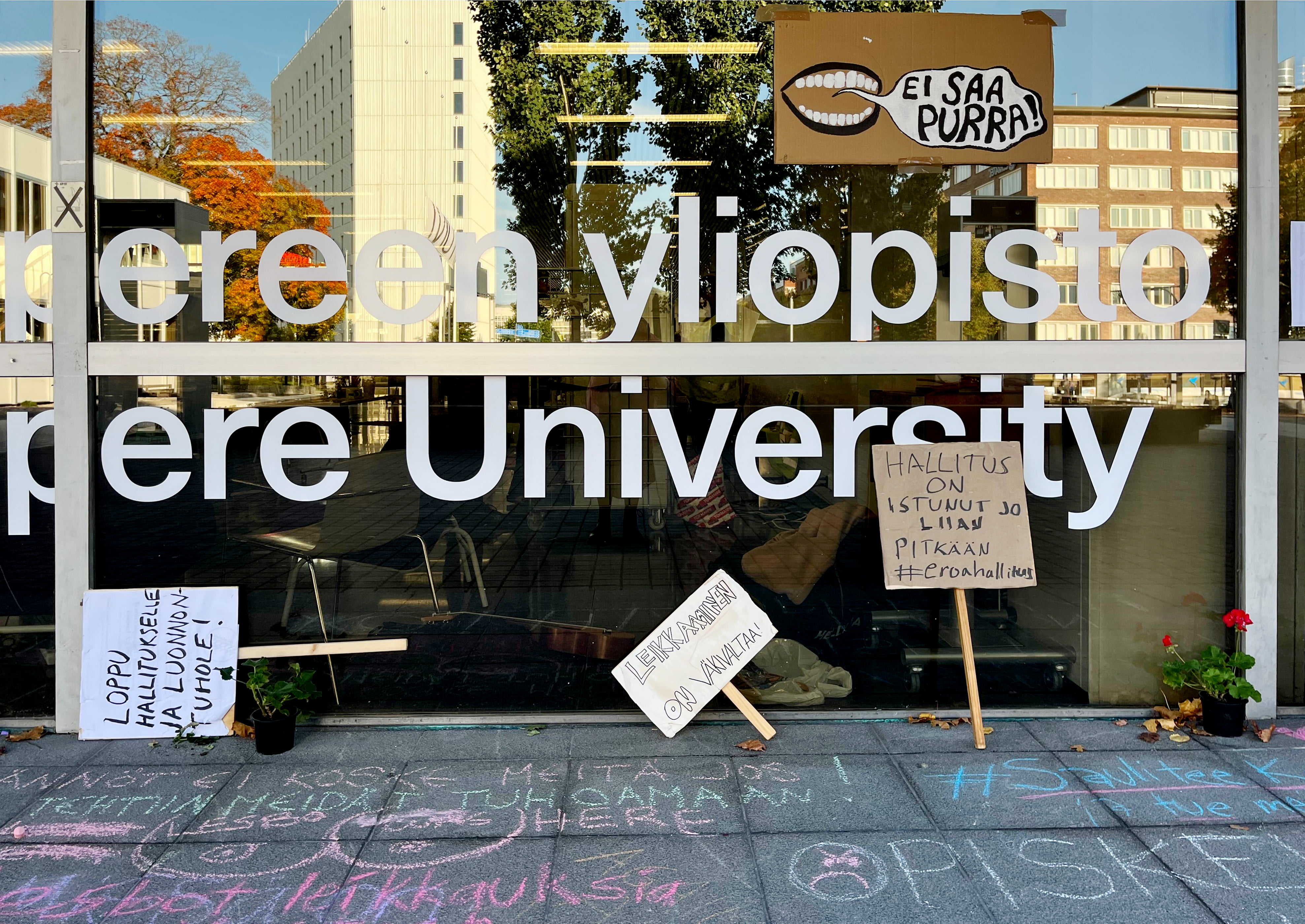 Valokuvassa mielenosoituskylttejä Tampereen yliopiston edustalla.