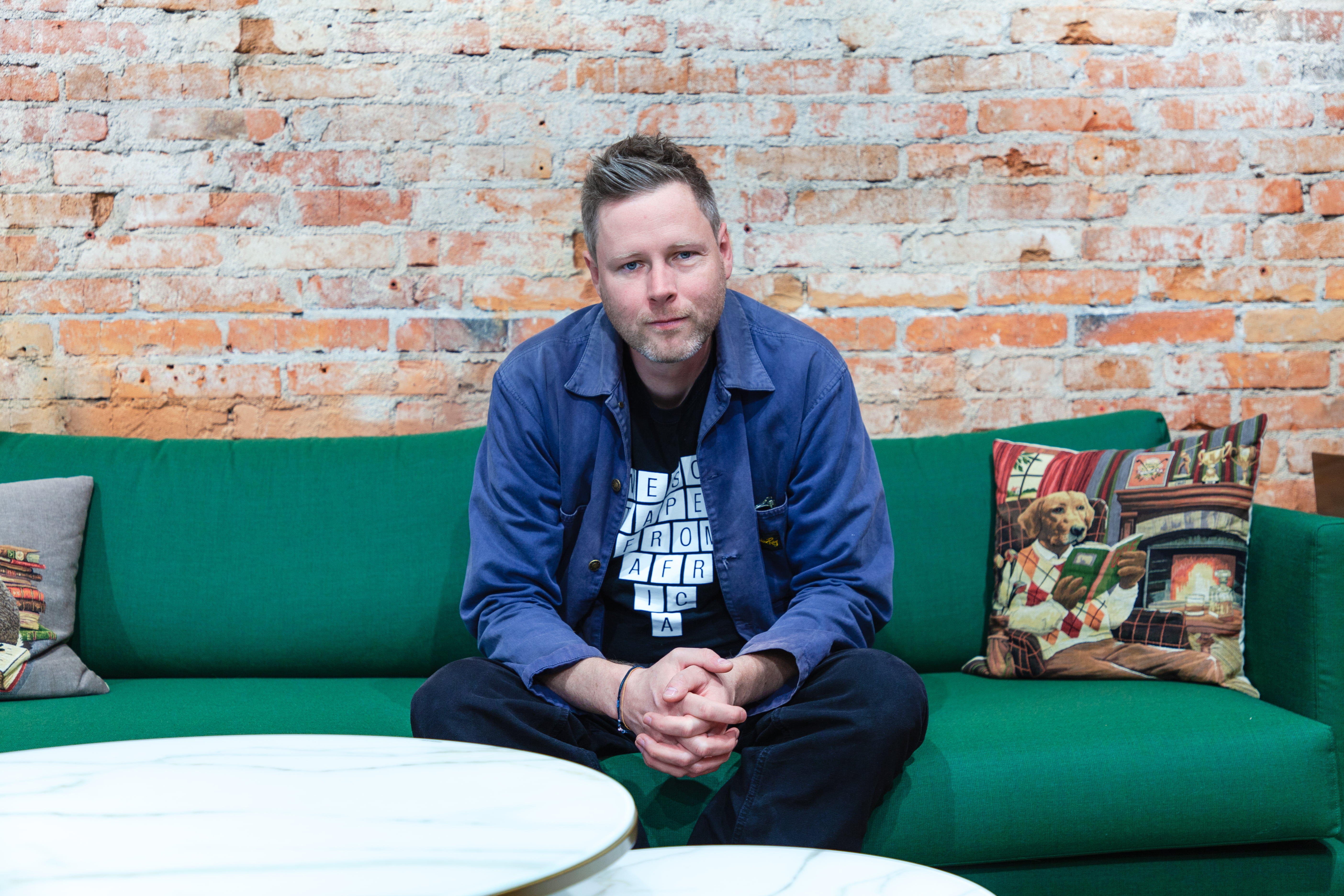 Max Porter istuu sohvalla, katsoo kameraan.