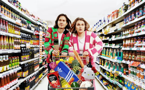 Samu Kuoppa ja Riina Tanskanen työntävät täyttä ostoskärryä kaupan tuotehyllyjen välissä