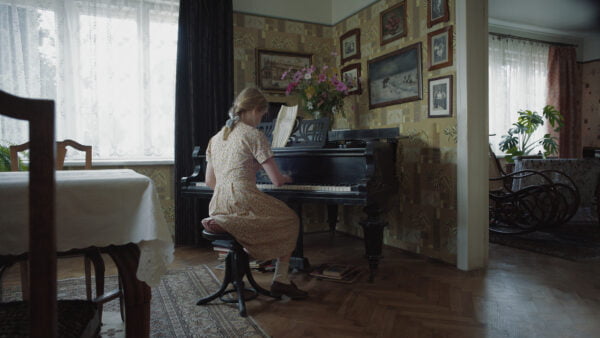 Tyttö soittaa pianoa porvarillisessa asunnossa
