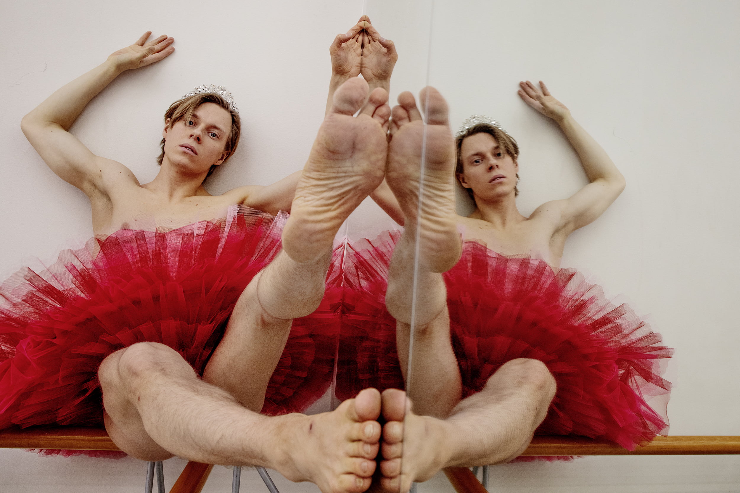 Kilpinen istuu penkillä punaisessa tanssimekossa paljaat jalat kohti kameraa