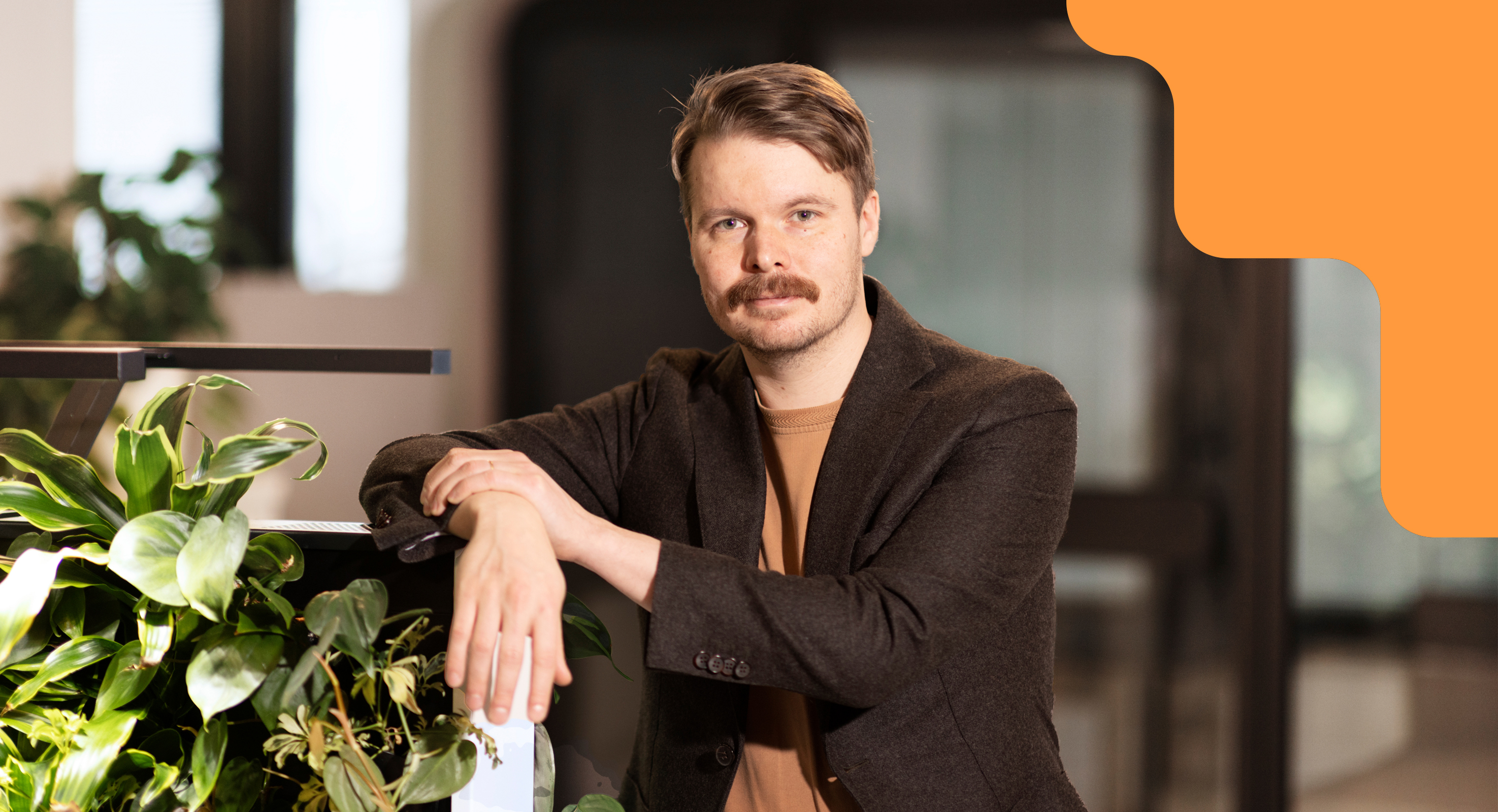 Olli Toivanen nojaa kukkaistutukseen toimistoympäristössä