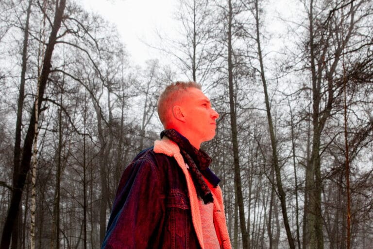 Asa katsoo ylöspäin, taustalla harmaata metsää. Asaan kohdistuu punainen valo.