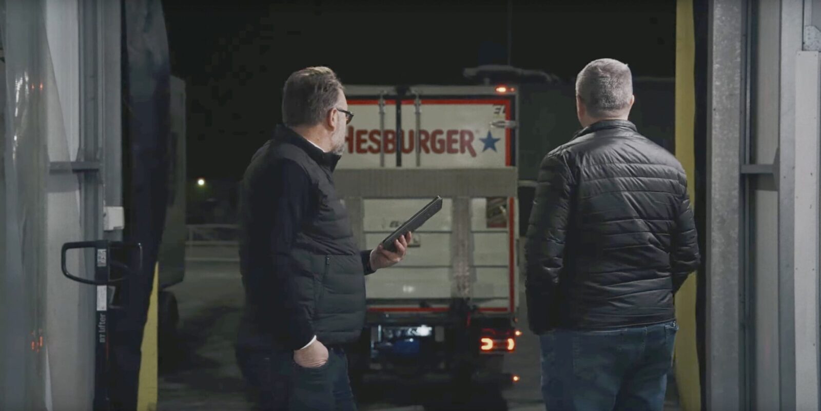 Marko Salmela ja Kari Salmela seisovat ulkona, taustalla rekka, jossa Hesburgerin logo.