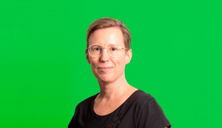 Johanna Ruohonen katsoo kameraan hymyillen, vihreä tausta.