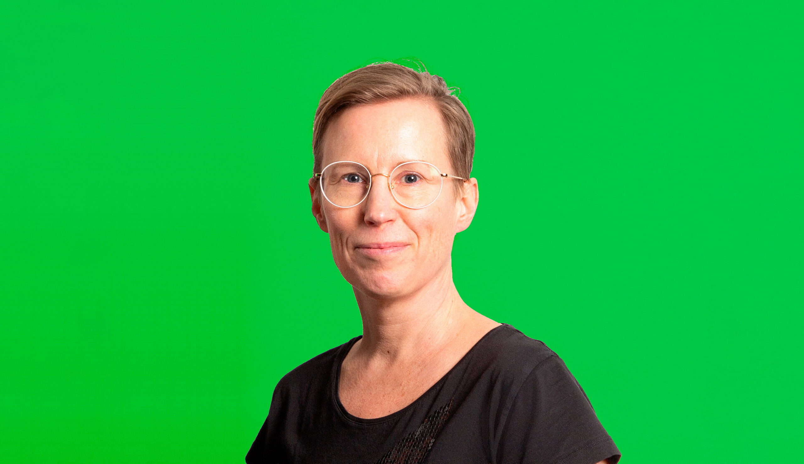 Johanna Ruohonen katsoo kameraan hymyillen, vihreä tausta.