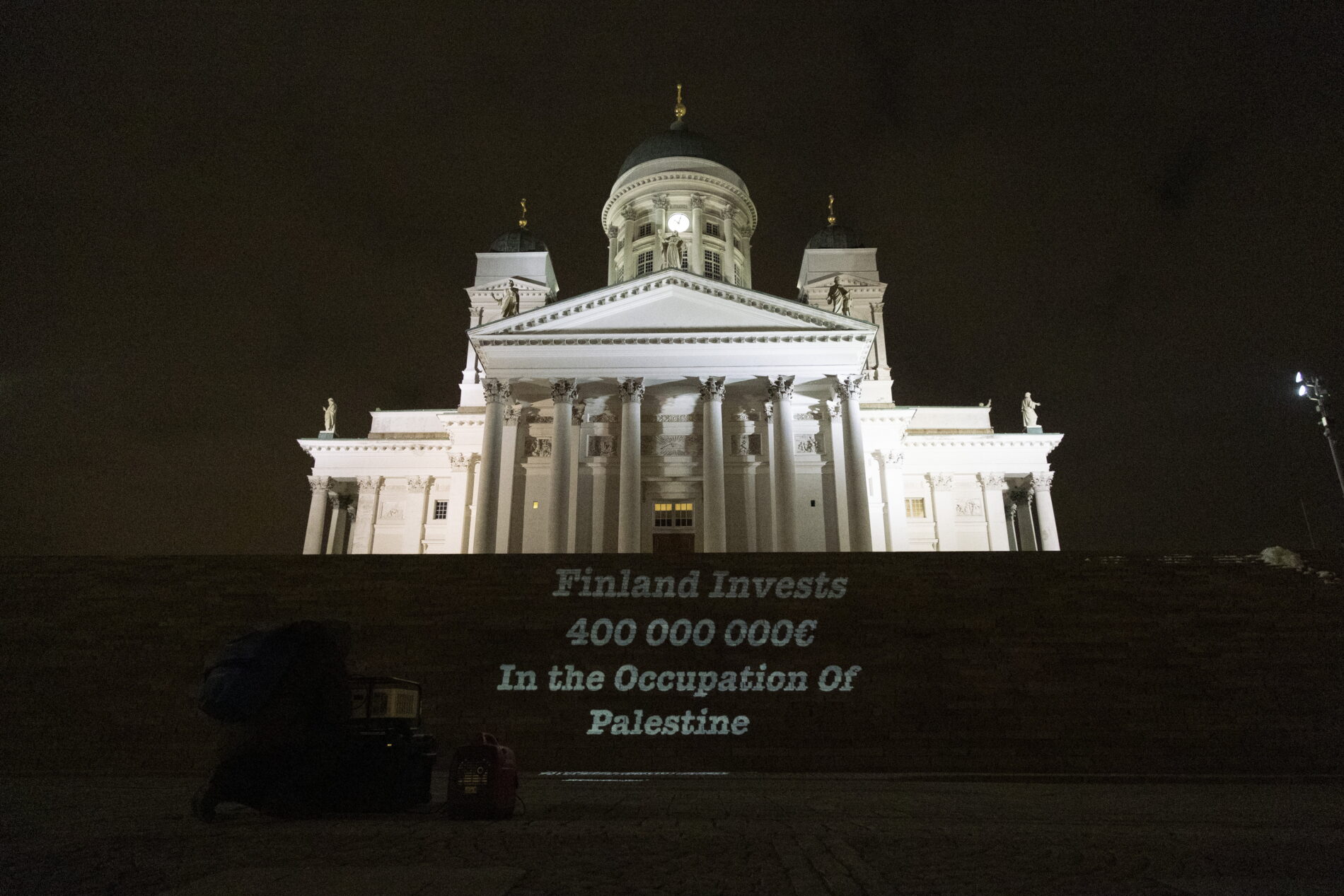 Teksti “Finland Invests 400 000 000 € in the Occupation of Palestine” heijastettu Tuomiokirkon portaille.