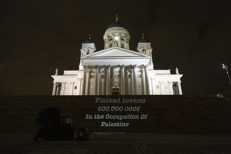 Teksti “Finland Invests 400 000 000 € in the Occupation of Palestine” heijastettu Tuomiokirkon portaille.