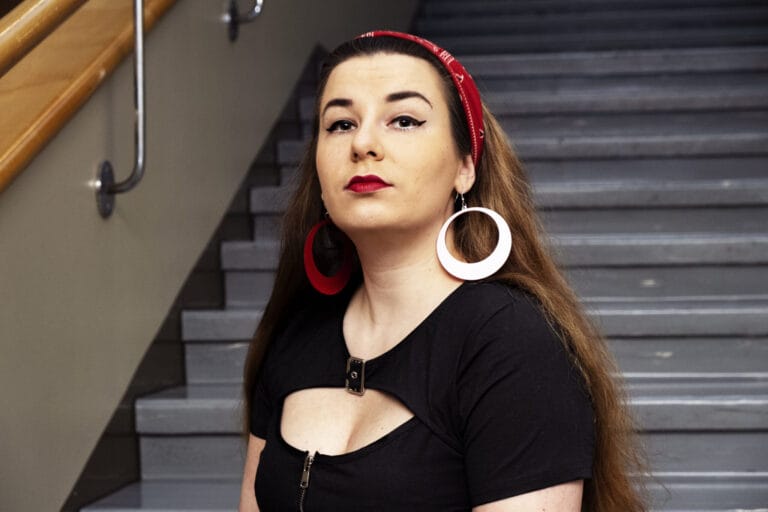 Linda-Maria Roine katsoo kameraan, taustalla rappukäytävän raput.