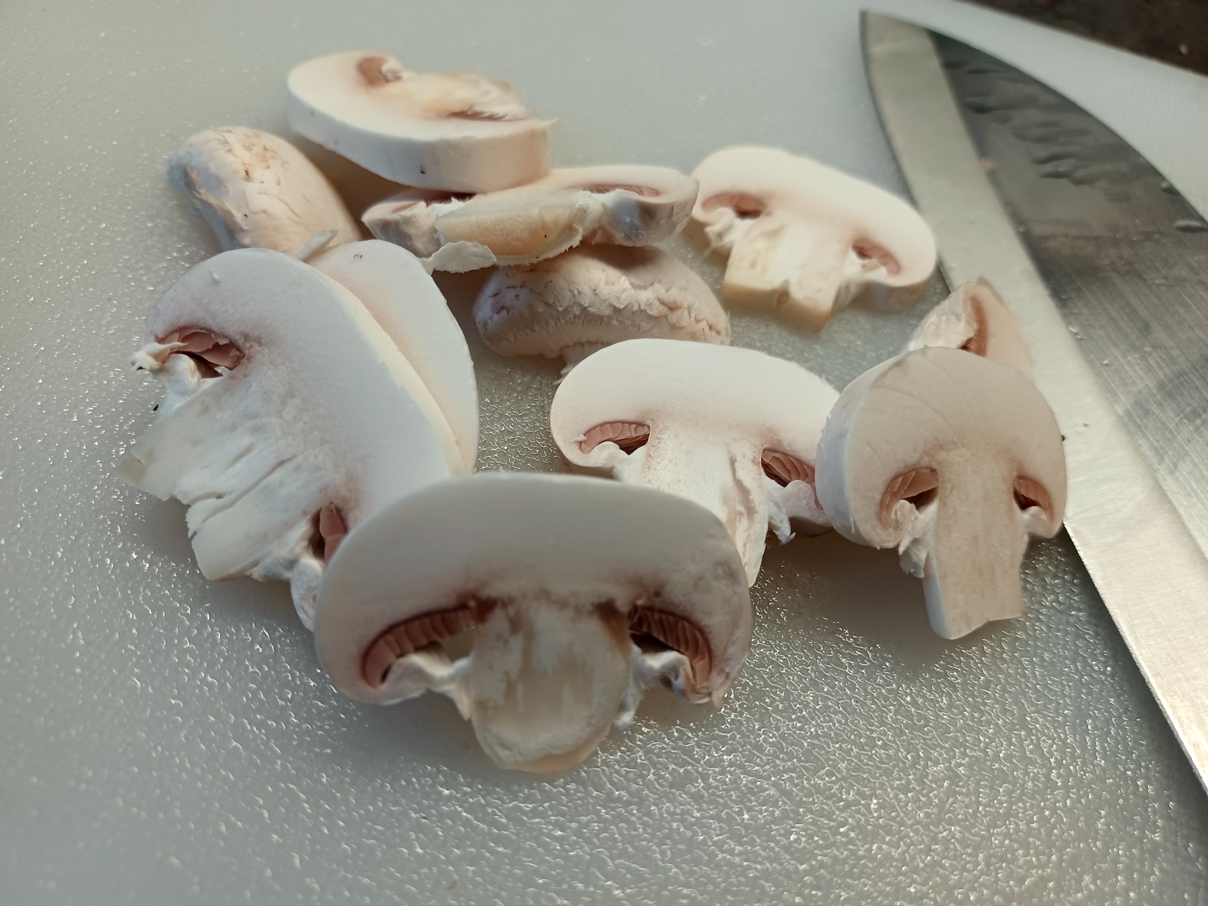 Pilkottuja herkkusieniä leikkuulaudalla veitsen vieressä
