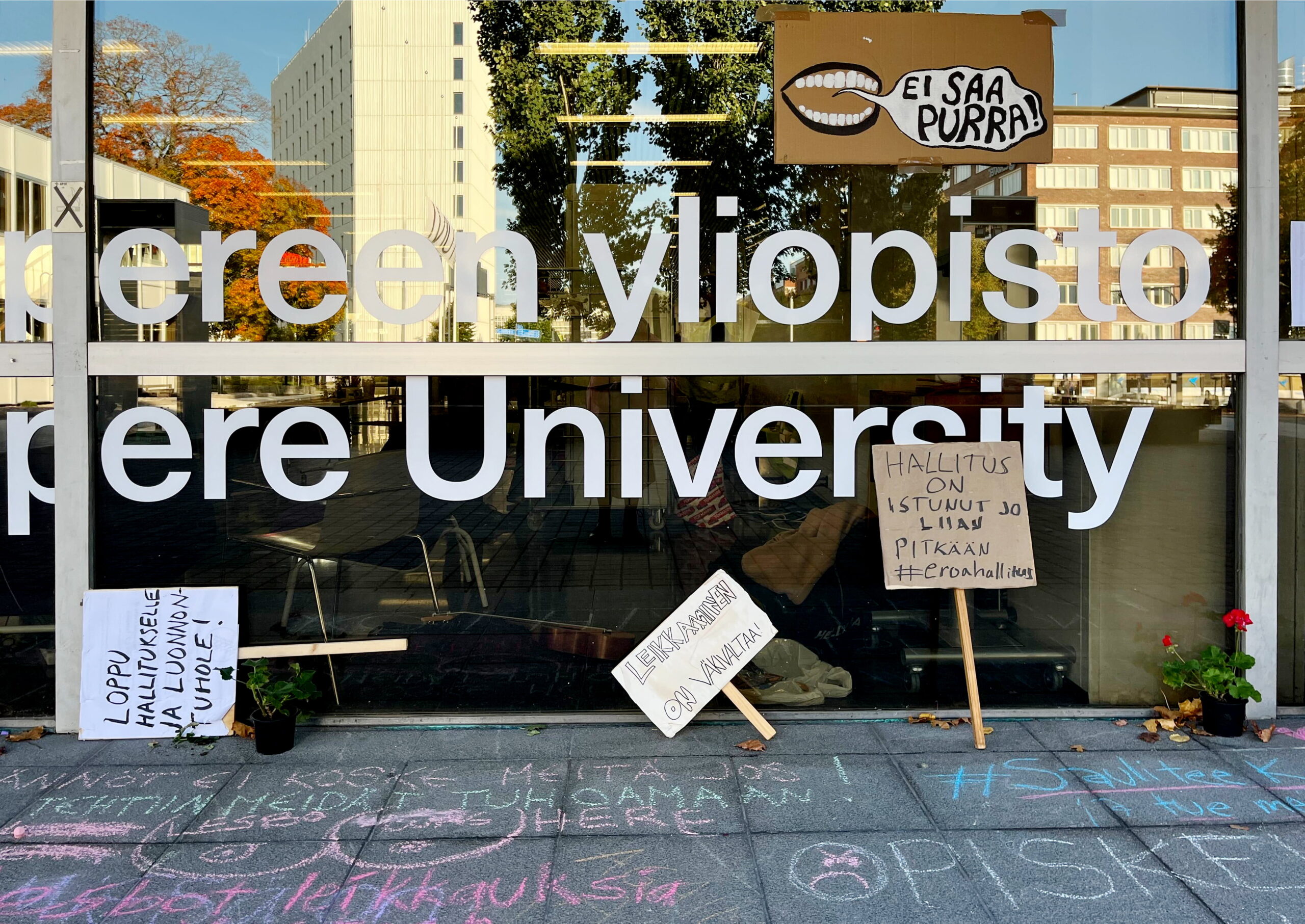 Valokuvassa mielenosoituskylttejä Tampereen yliopiston edustalla.