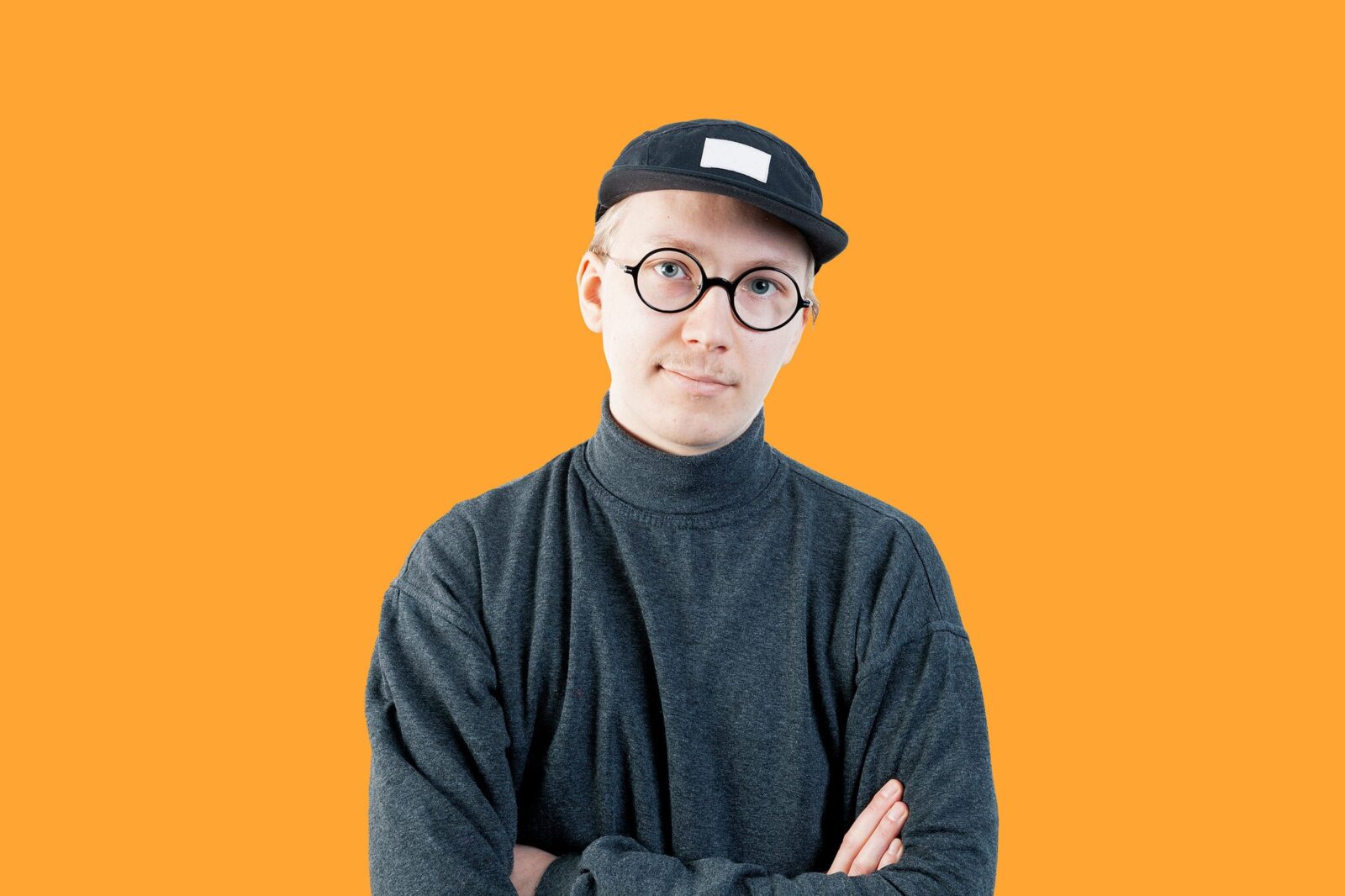 Vilppu Rantanen katsoo kameraan, oranssi tausta.