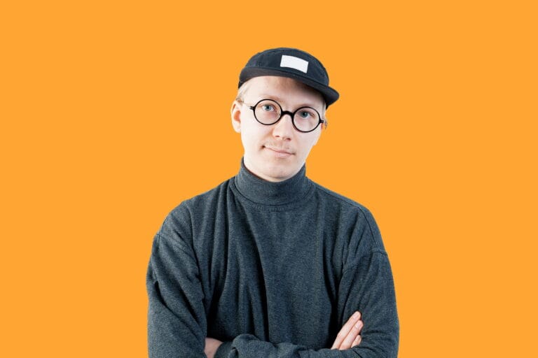 Vilppu Rantanen katsoo kameraan, oranssi tausta.